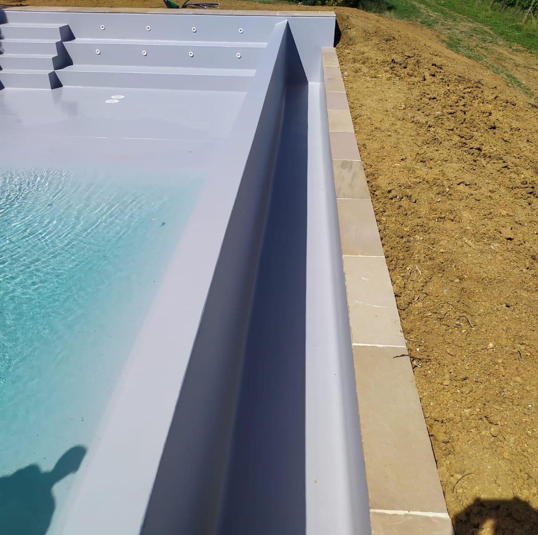 Piscina a sfioro su un lato con telo grigio chiaro