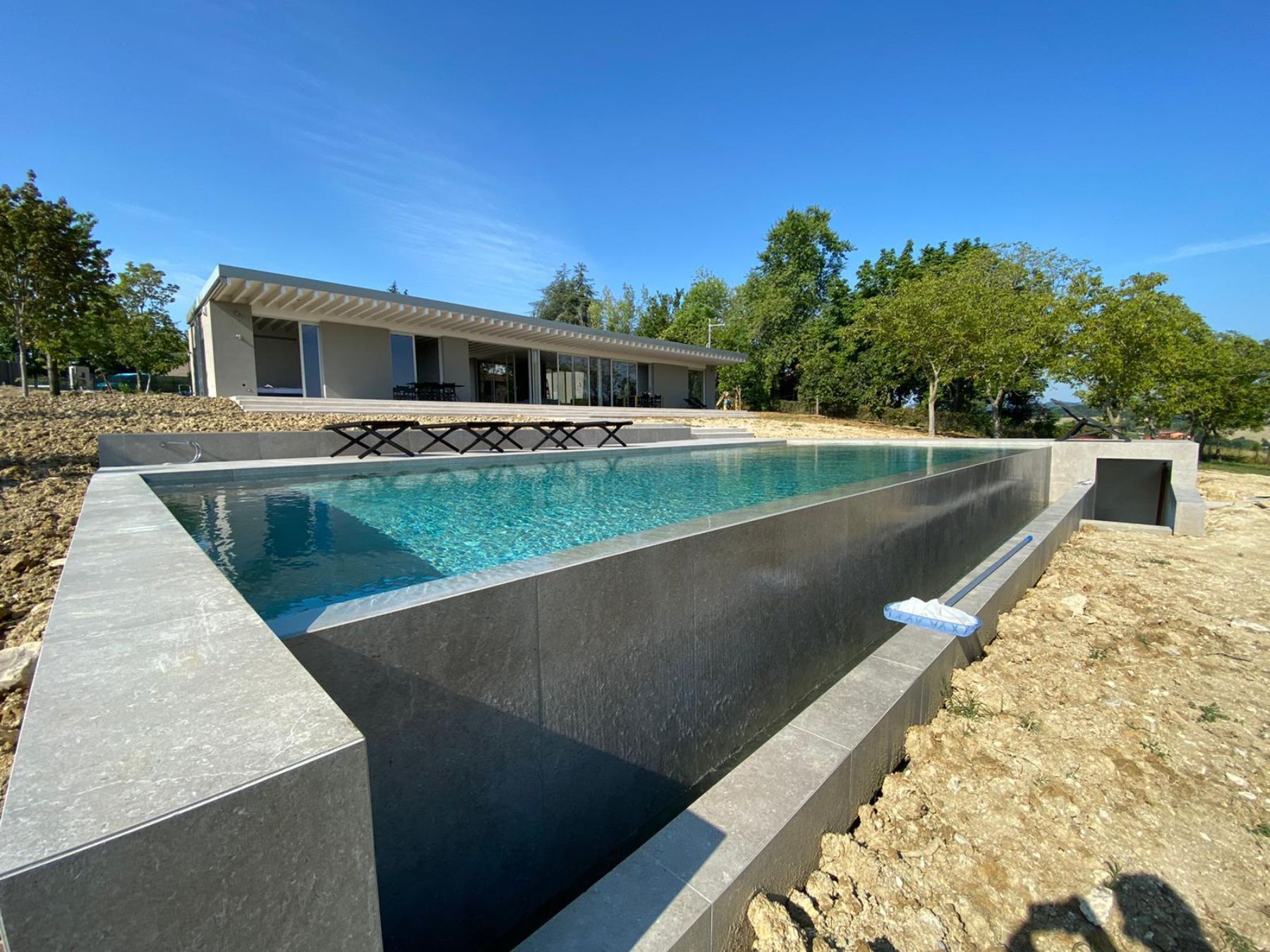 Piscina a sfioro con tracimazione su un lato. Piscina a sfioro con tracimazione su un lato.