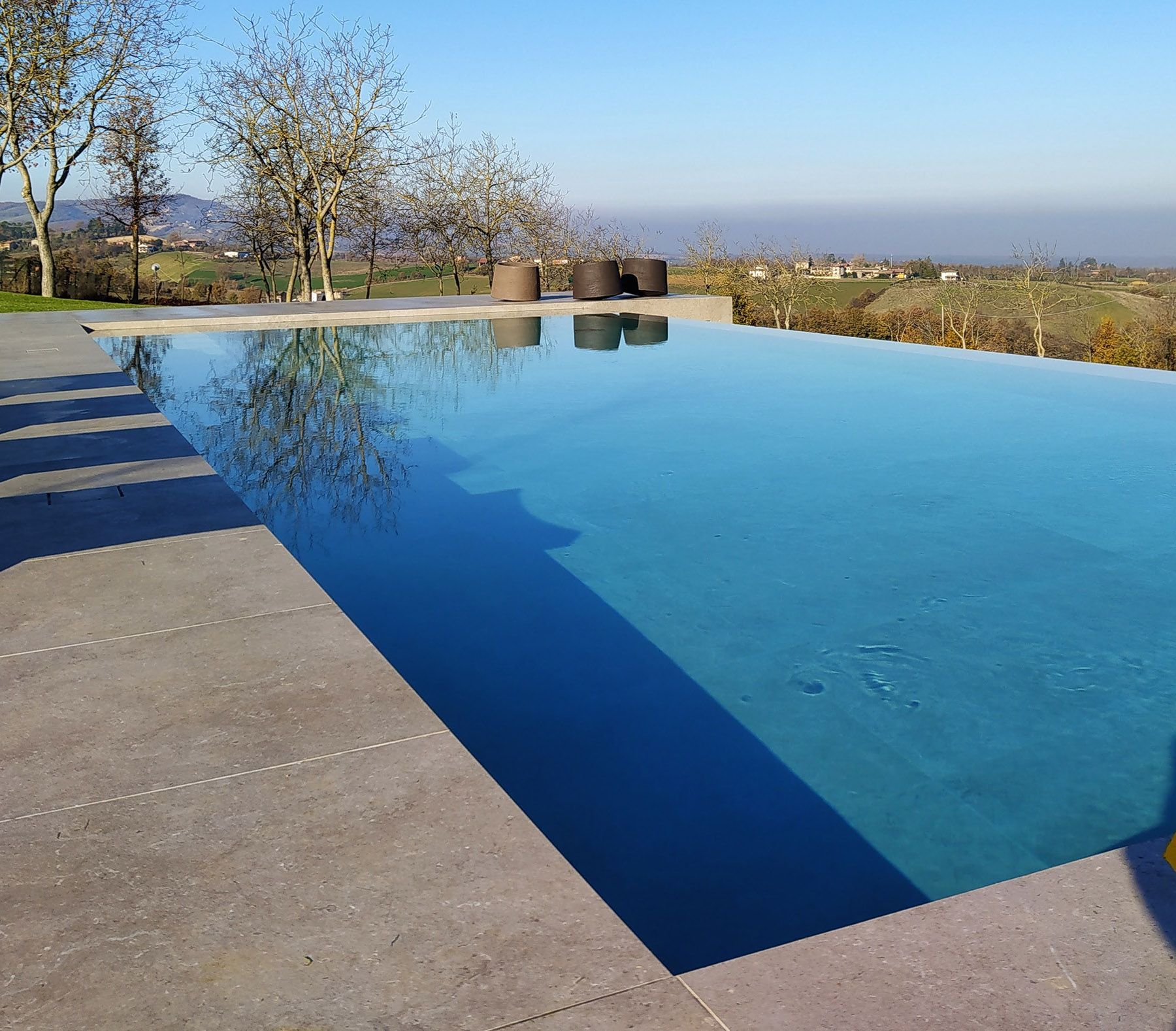 Piscina a sfioro con tracimazione su un lato. Piscina a sfioro con tracimazione su un lato.