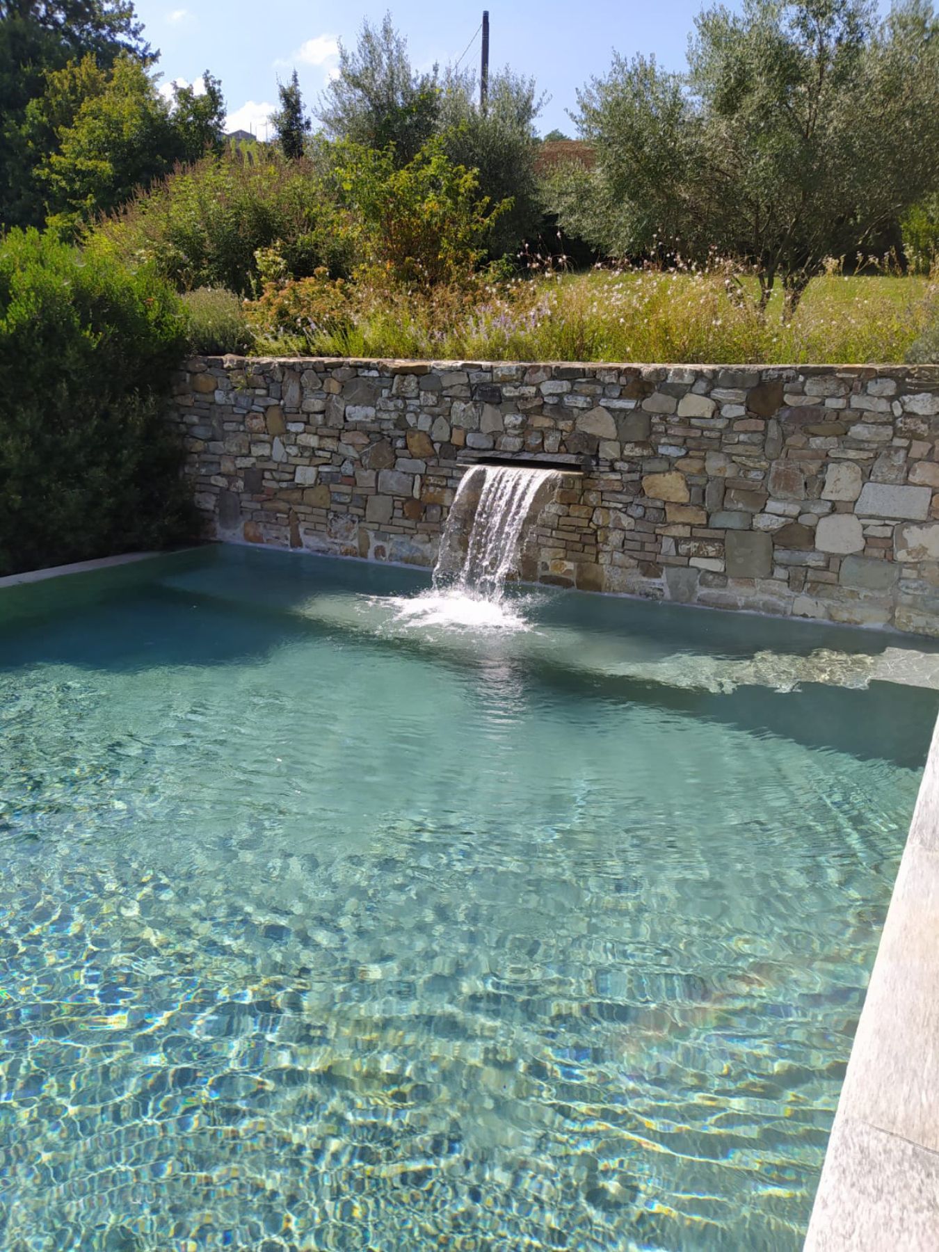 Piscina a sfioro su un lato con cascata e idromassaggio